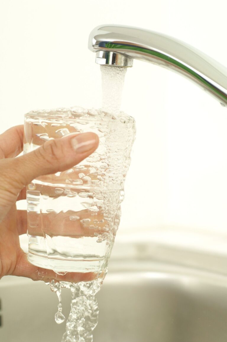 Cloudy tap water filling a clear glass at the kitchen sink