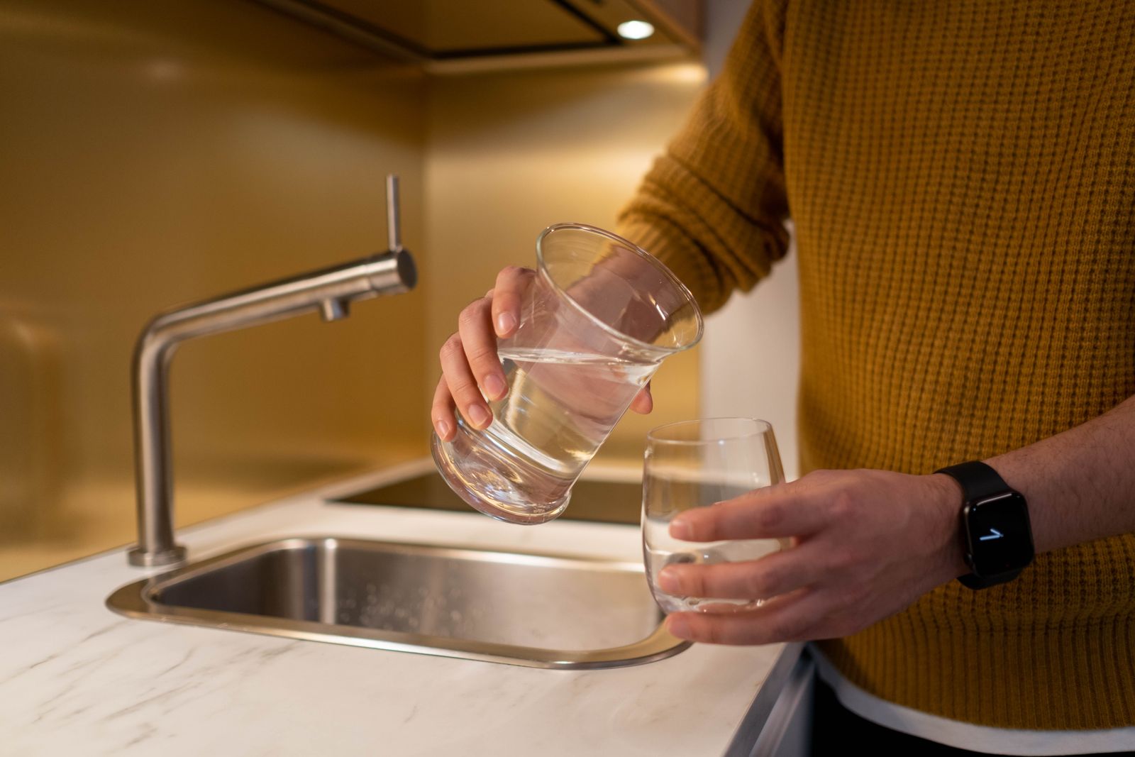 Pouring filtered drinking water into a clear glass to test for cloudy tap water
