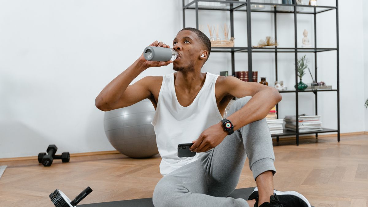 Man drinking a glass of filtered water for hydration after a workout