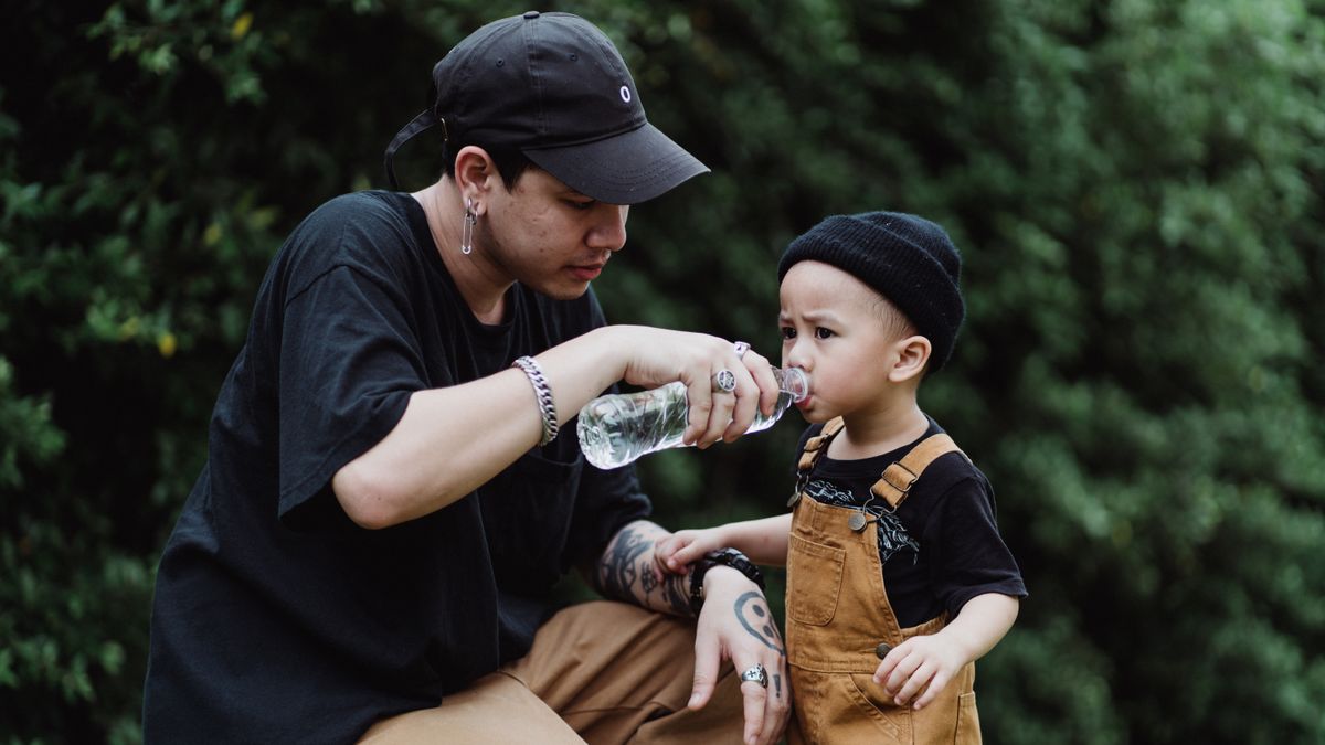 Father helping his son drink safe filtered water outdoors