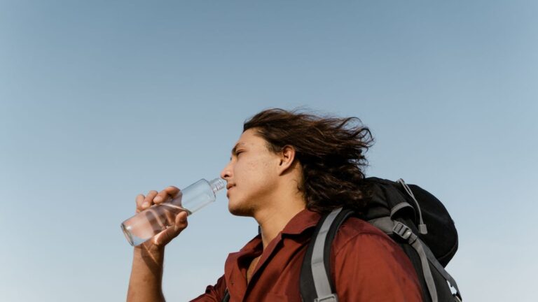 Psychology of thirst, man drinking water from a bottle while hiking outdoors